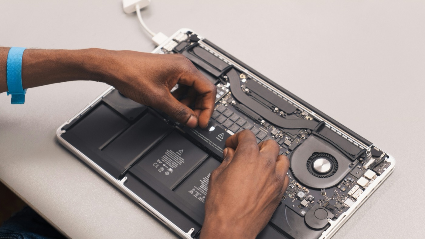 Hands repairing a donated laptop